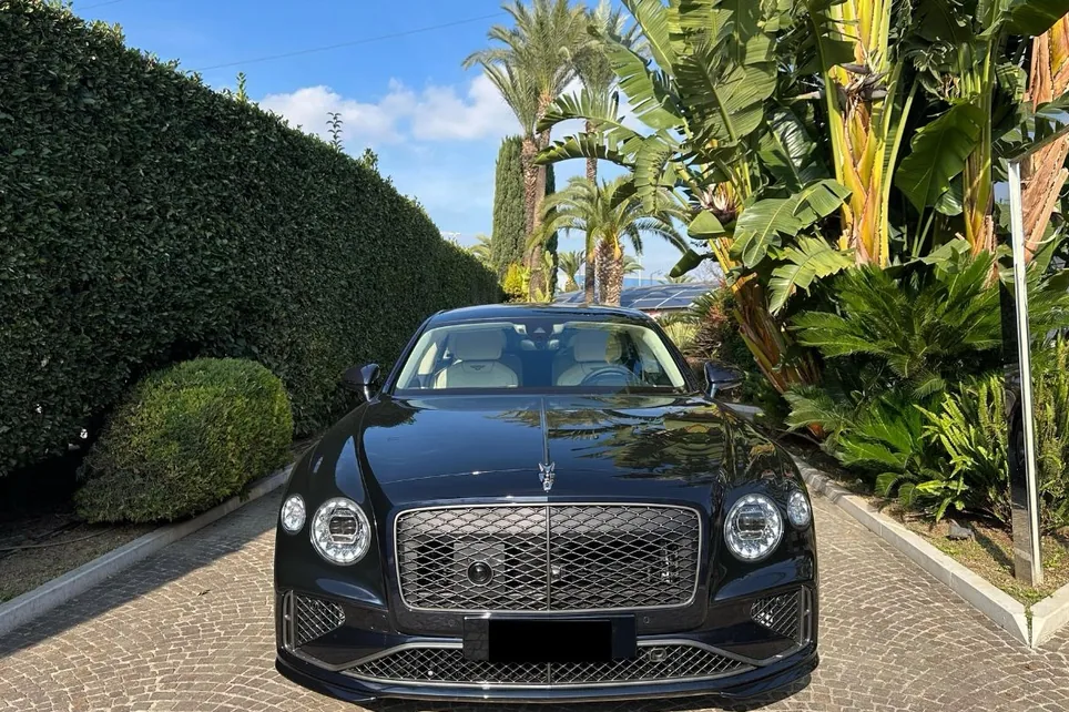 Bentley Flying Spur Élysium Drive devant un hôtel, entre les palmiers